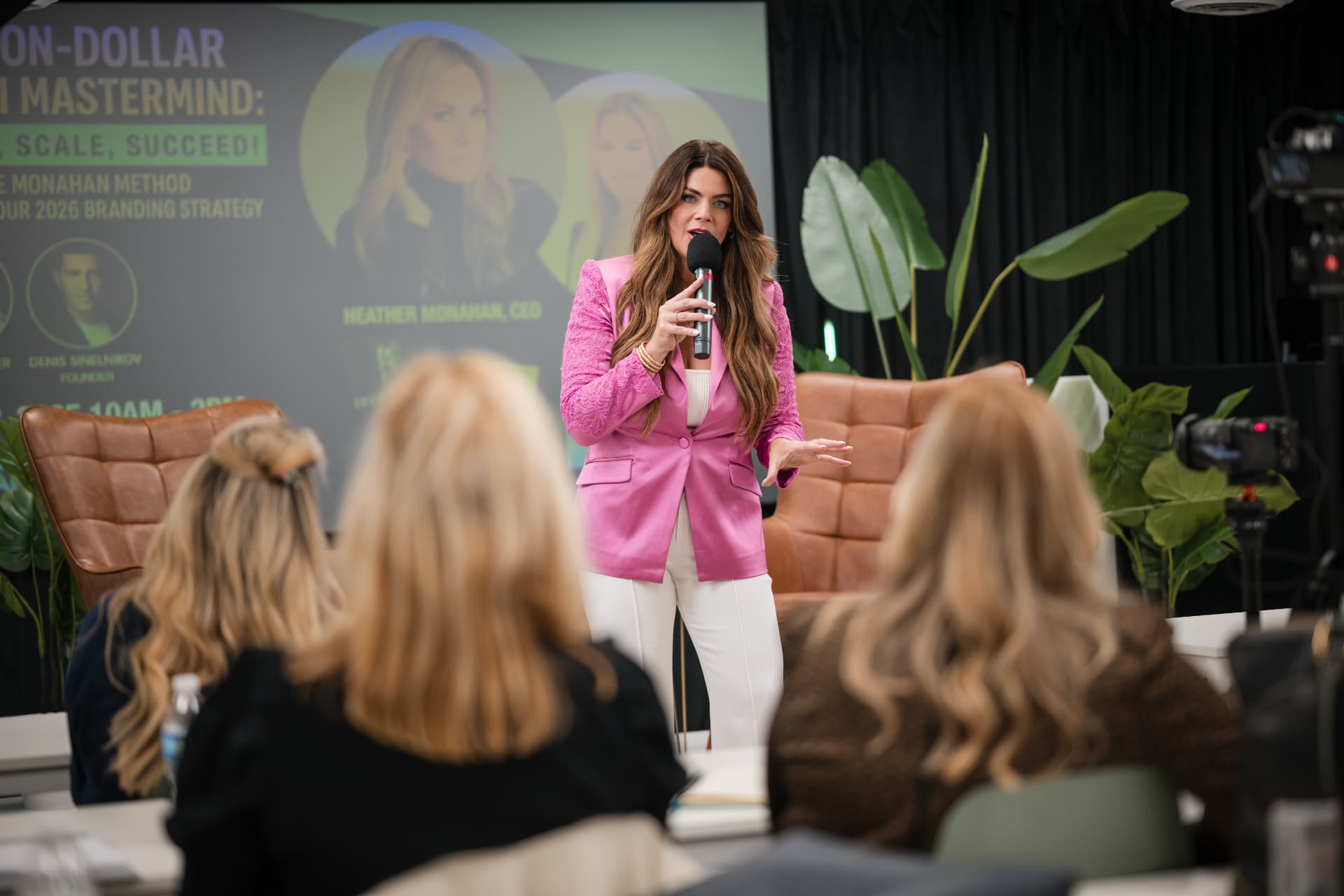 Speaker in a pink blazer addressing the Miami Mastermind audience